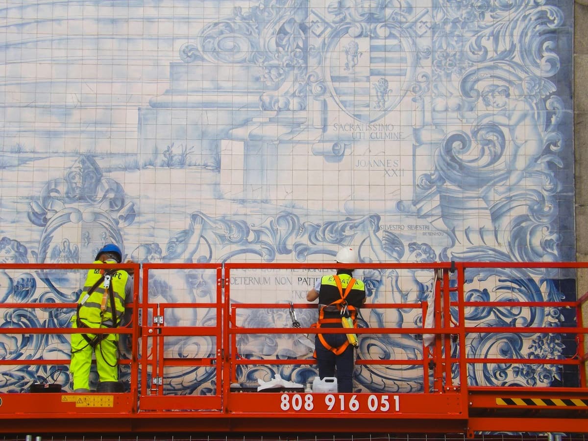 Workers restore large blue and white tile mural